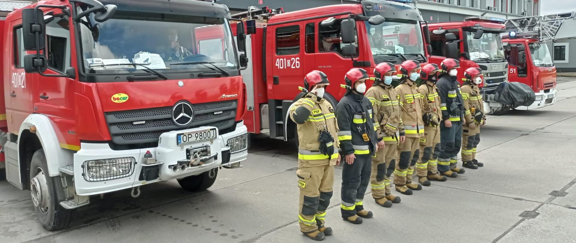 Na zdjęciu widoczni strażacy oddający hołd w geście solidarności i ku czci zastrzelonego 4 maja 2021 roku w Raciborzu policjanta. Strażacy przed jednostką ratowniczo-gaśniczą PSP.