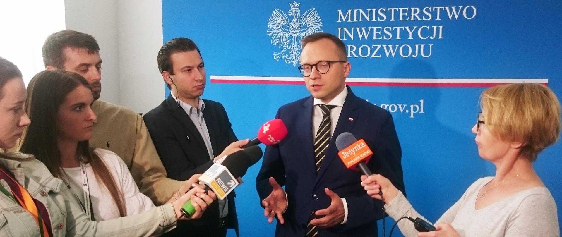 wiceminister Artur Soboń mówi do mikrofonów, które trzymają dziennikarze