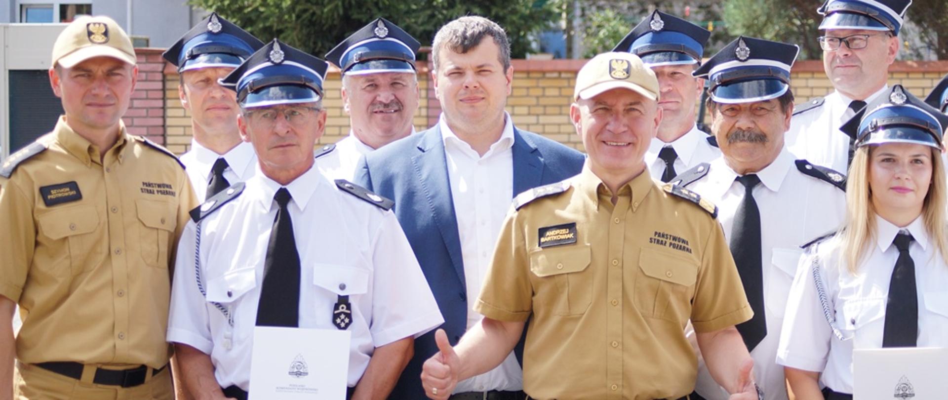 Komendant Bartkowiak pozuje do zdjęcia grupowego ze strażakami OSP i PSP. 