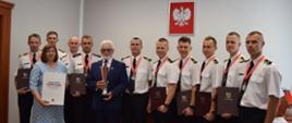 SPOTKANIE STRAŻAKÓW ZE STAROSTĄ. Na zdjęciu funkcjonariusze stoją w rzędzie razem ze starostą i wicestarostą do pamiątkowego zdjęcia. 