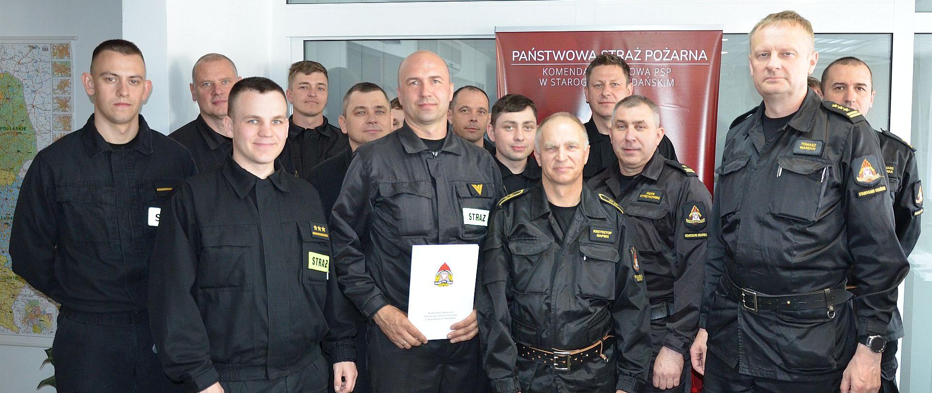 Zdjęcie przedstawia Komendanta Powiatowego, nagrodzonego funkcjonariusza oraz funkcjonariuszy ze zmiany.