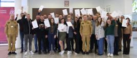 Pamiątkowe zdjęcie grupowe uczestników szkolenia inspektorów ochrony przeciwpożarowej (26 osób) w towarzystwie Zastępcy Komendanta Centralnej Szkoły PSP, kobiety oraz dwóch funkcjonariuszy CS PSP