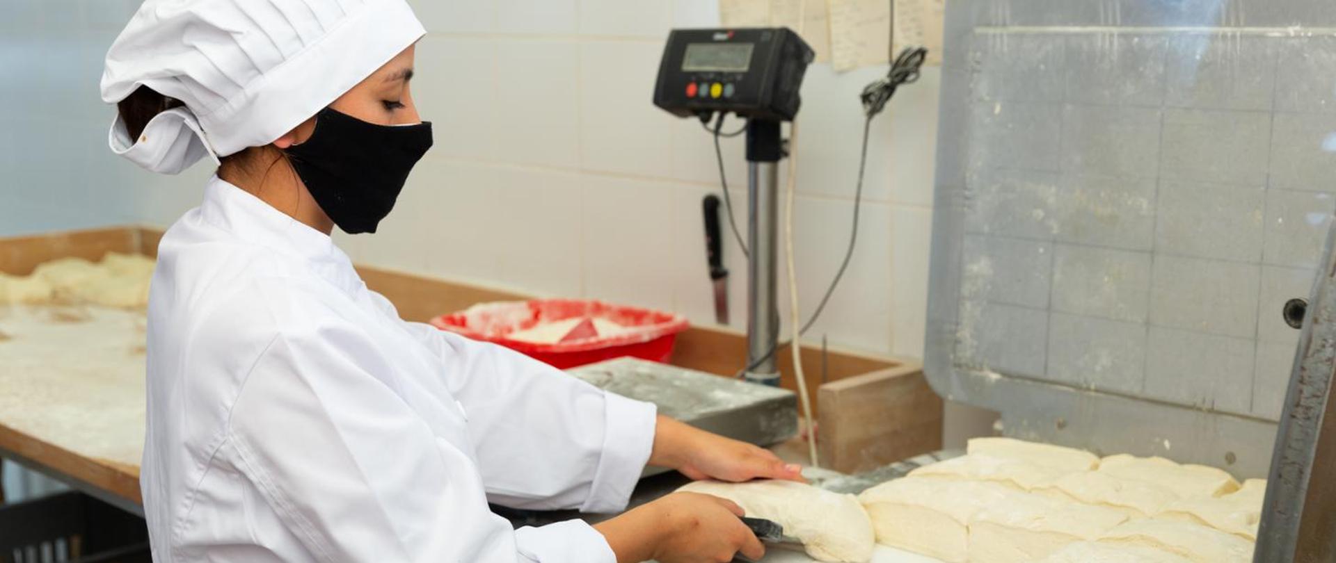 Na zdjęciu pokazany jest pracownik podczas prac przygotowujących do wypieku chleba. 