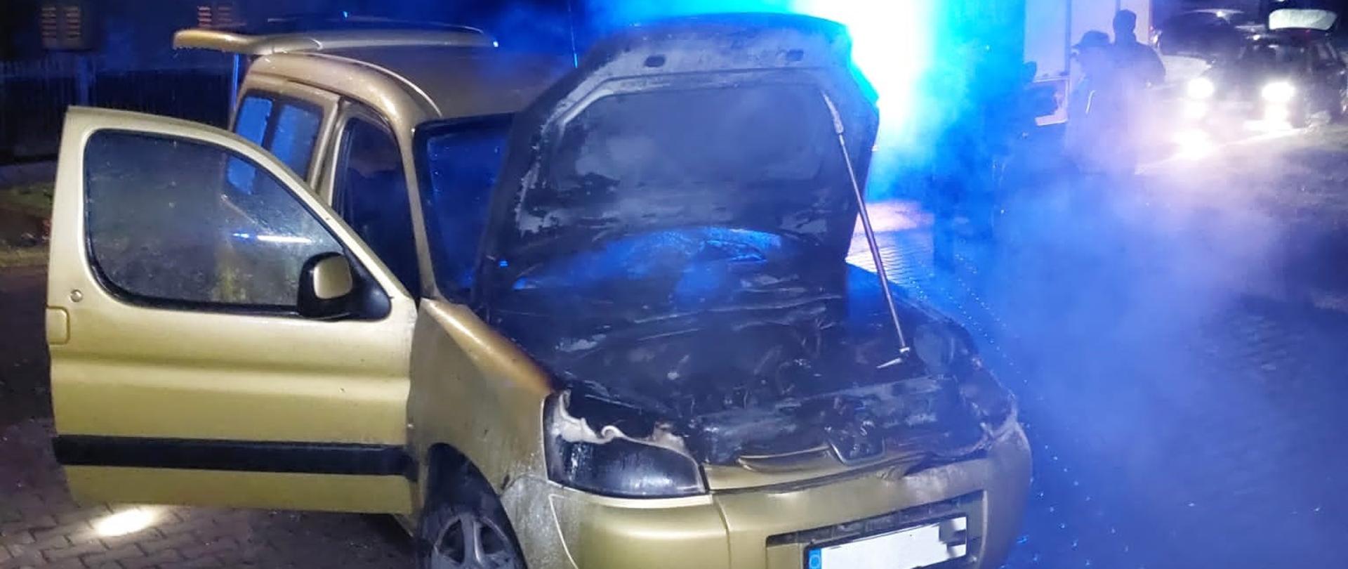 Zdjęcie przedstawia spalony samochód osobowy. Pod otwarta maską widać zniszczoną komorę silnika.