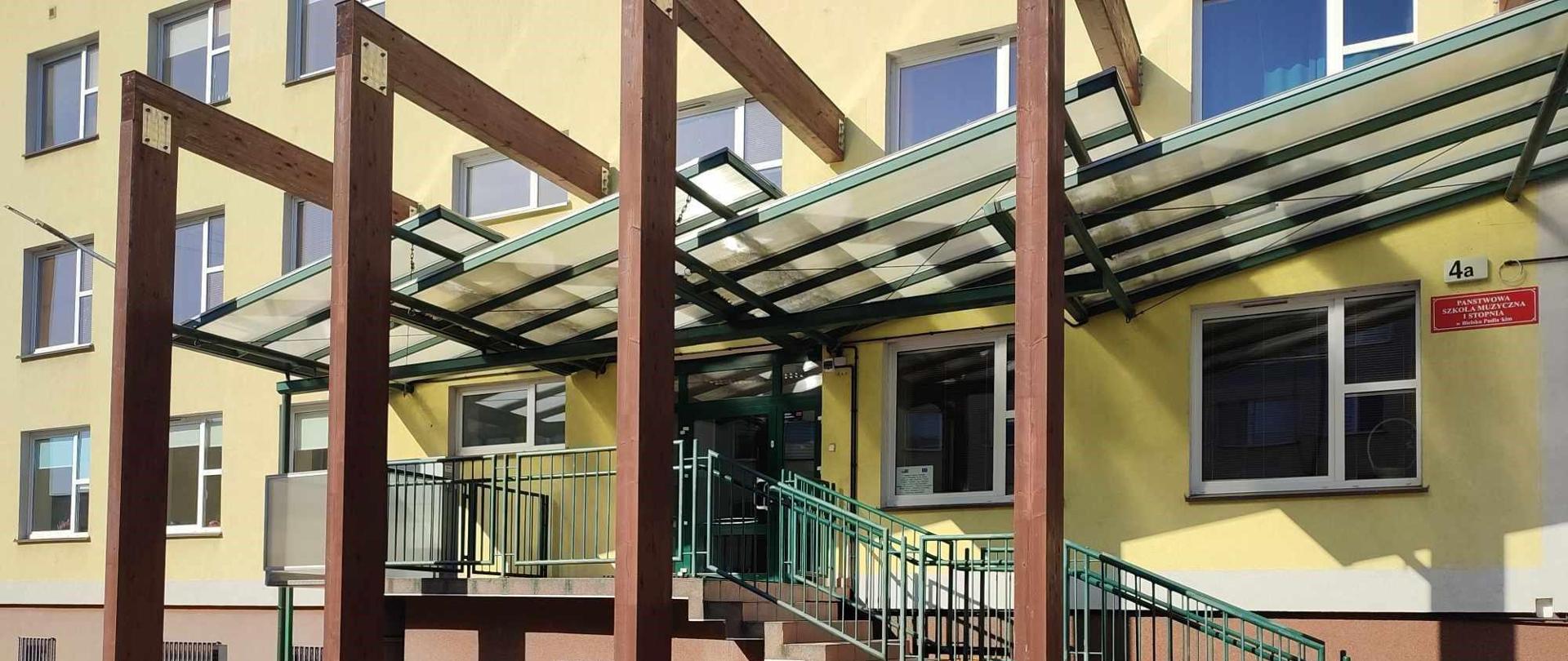 Na zdjęciu grupa kilkunastu "maluchów" trzyma węża maskotkę . Stoją na tle wejścia do szkoły.