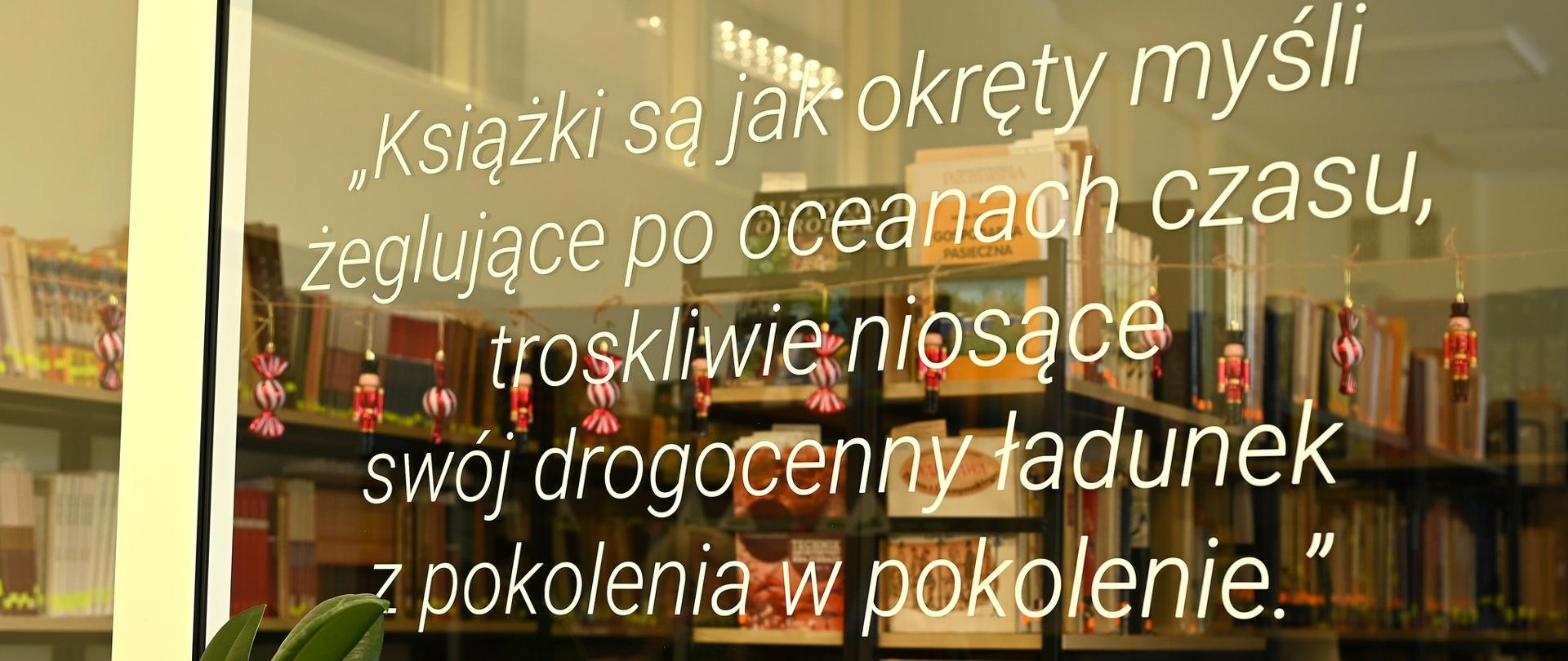 zdjęcie przedstawia witrynę w bibliotece i za nią są wyeksponowane książki na regałach 