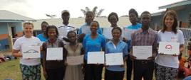 Dwie Polki w koszulach z logo Polskiej pomocy i nauczyciele afrykańskie z zaświadczeniami o ukończonym szkoleniu