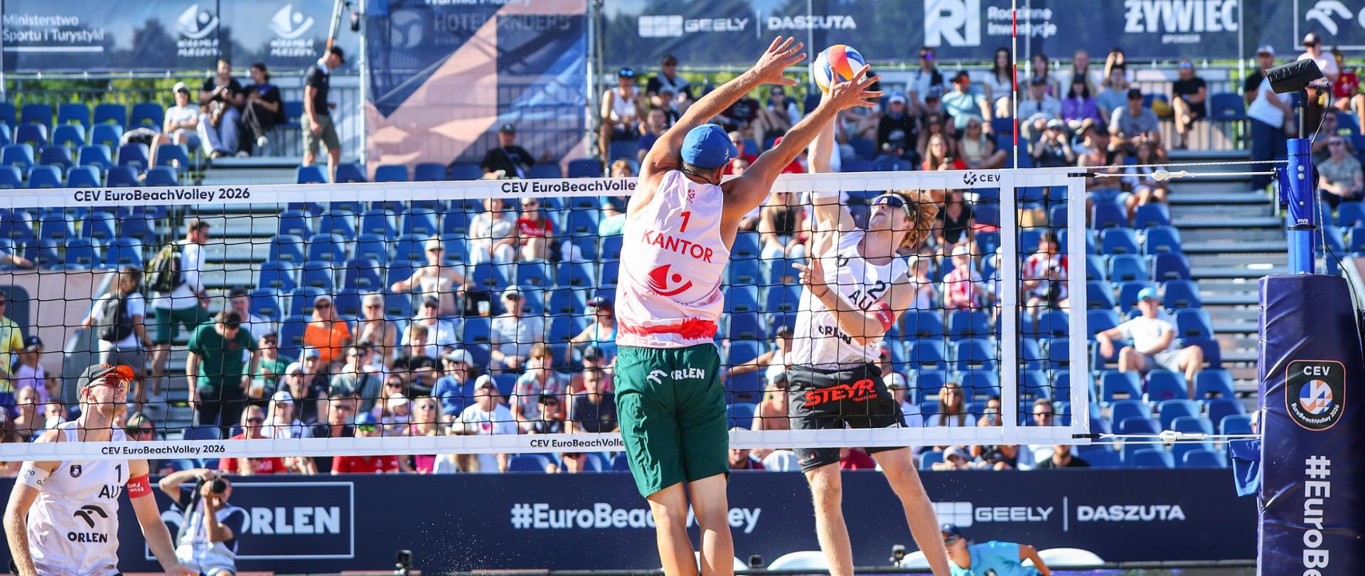 Mecz siatkówki plażowej mężczyzn. W tle trybuny.