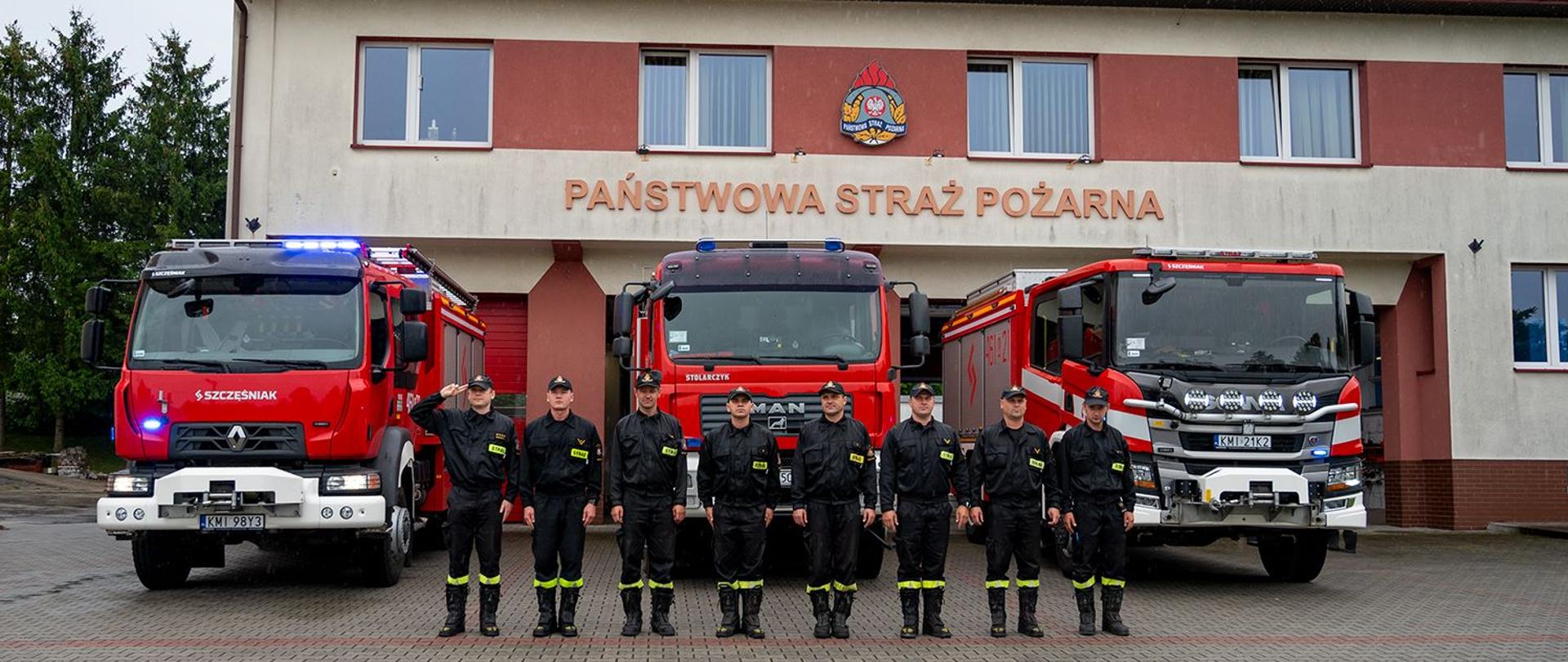 Na zdjęciu widoczni Funkcjonariusze JRG w Miechowie oddajach hołd Powstańcom Warszawskim na tle Budynku JRG i samochodów pożarniczych