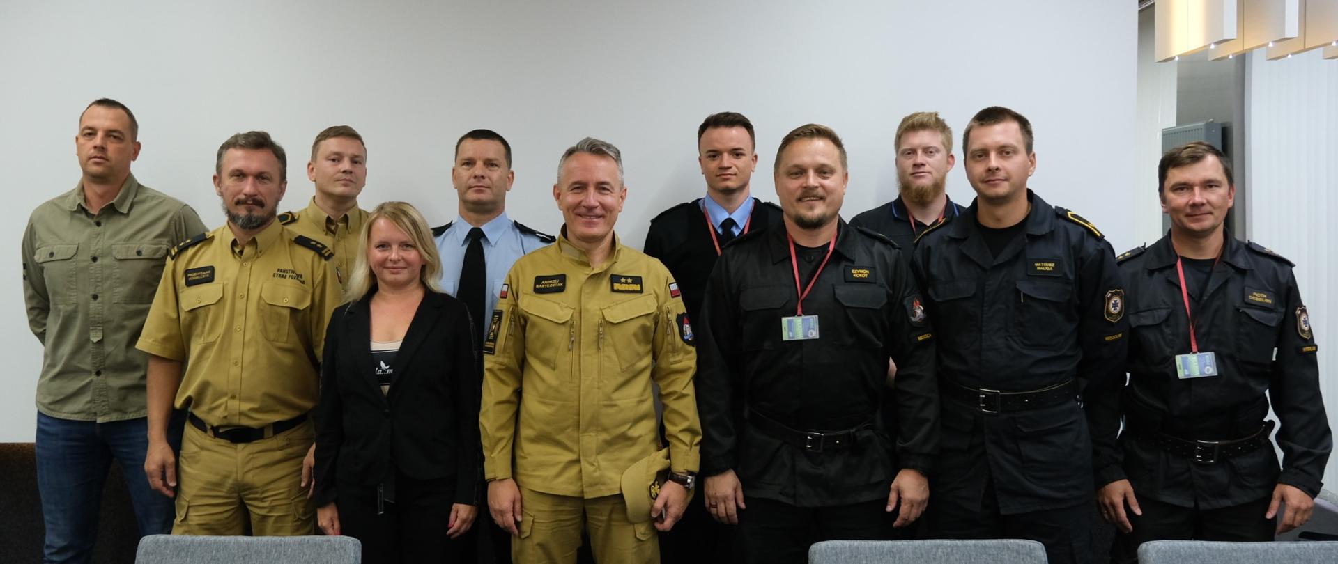 Na zdjęciu widać 11 strażaków podczas zdjęcia grupowego. Na środku stoi komendant główny PSP.