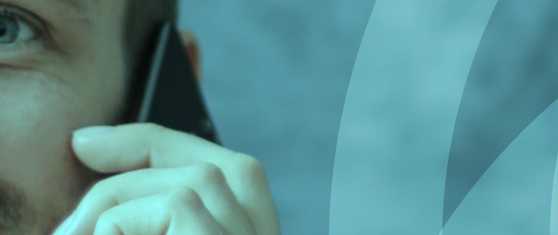 Na zdjęciu widoczny jest mężczyzna trzymający telefon komórkowy przy uchu. 