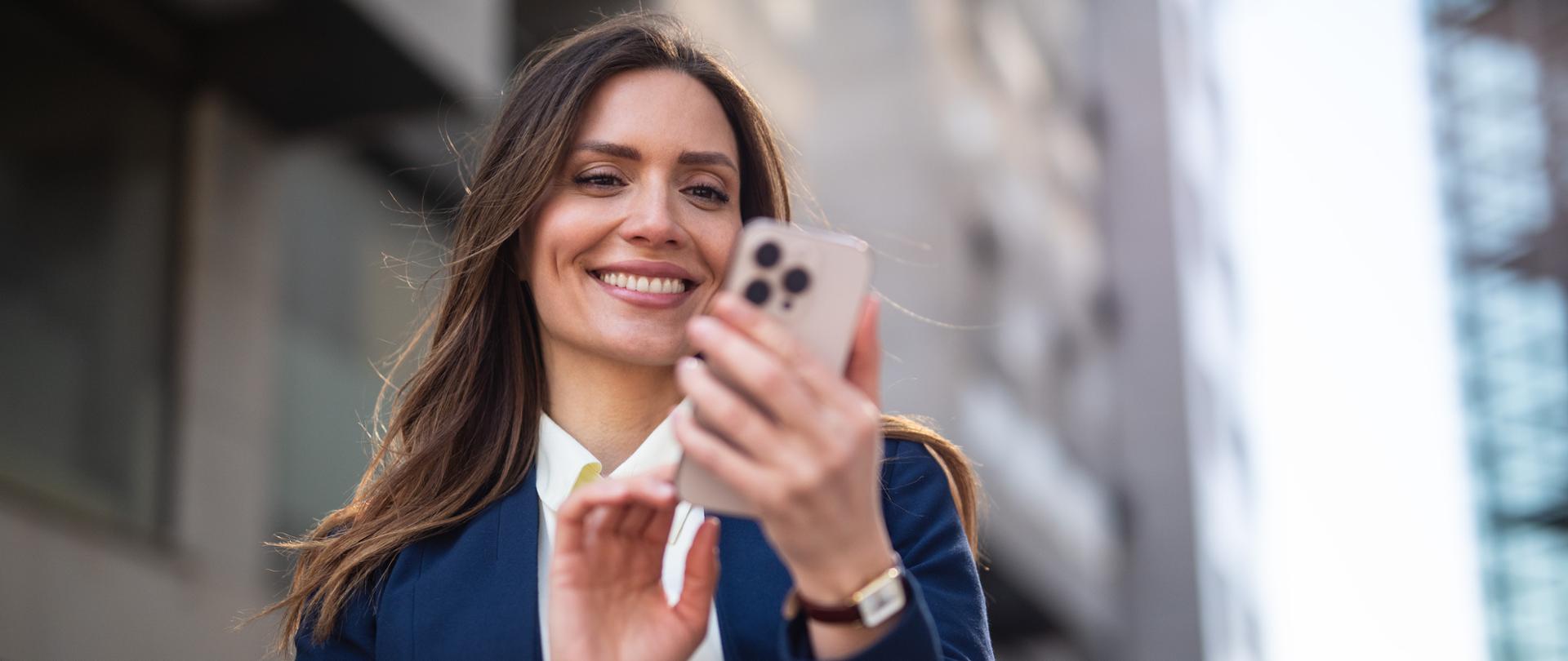 Młoda kobieta korrzystająca z telefonu komórkowego na ulicy