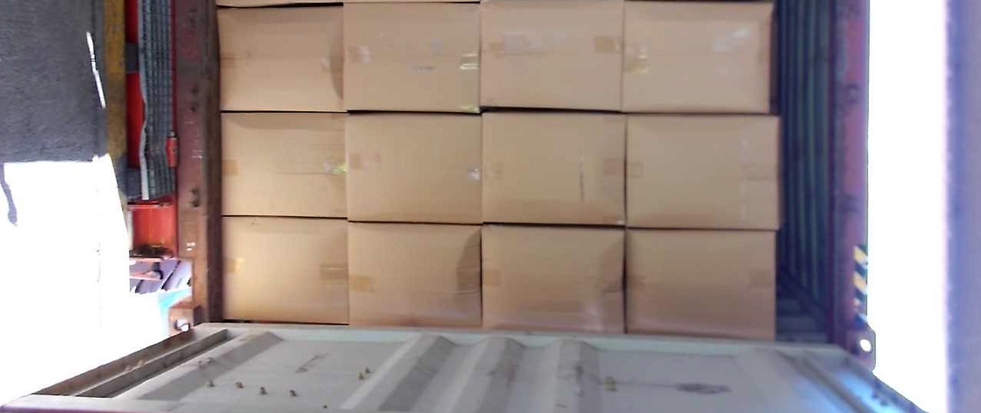 Otwarty kontener, w którym znajdują się ułożone kontenery.