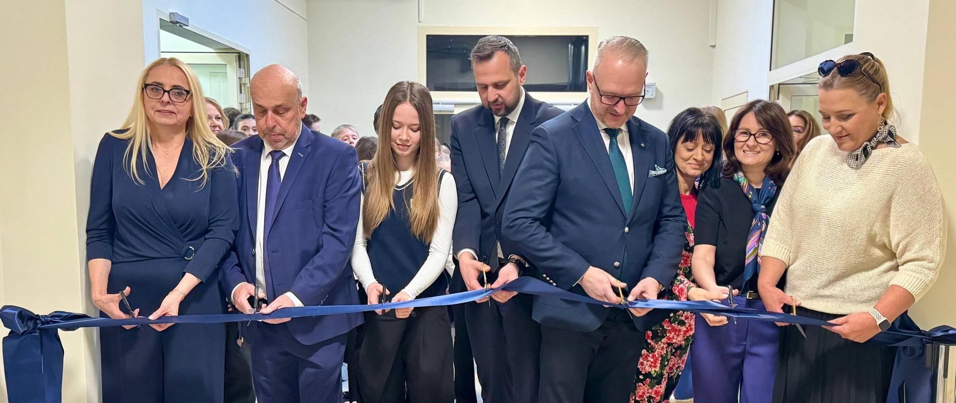 Grupa oficjeli przecina granatową wstążkę, symbolicznie, na znak otwarcia kompleksu sportowego