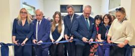 Grupa oficjeli przecina granatową wstążkę, symbolicznie, na znak otwarcia kompleksu sportowego
