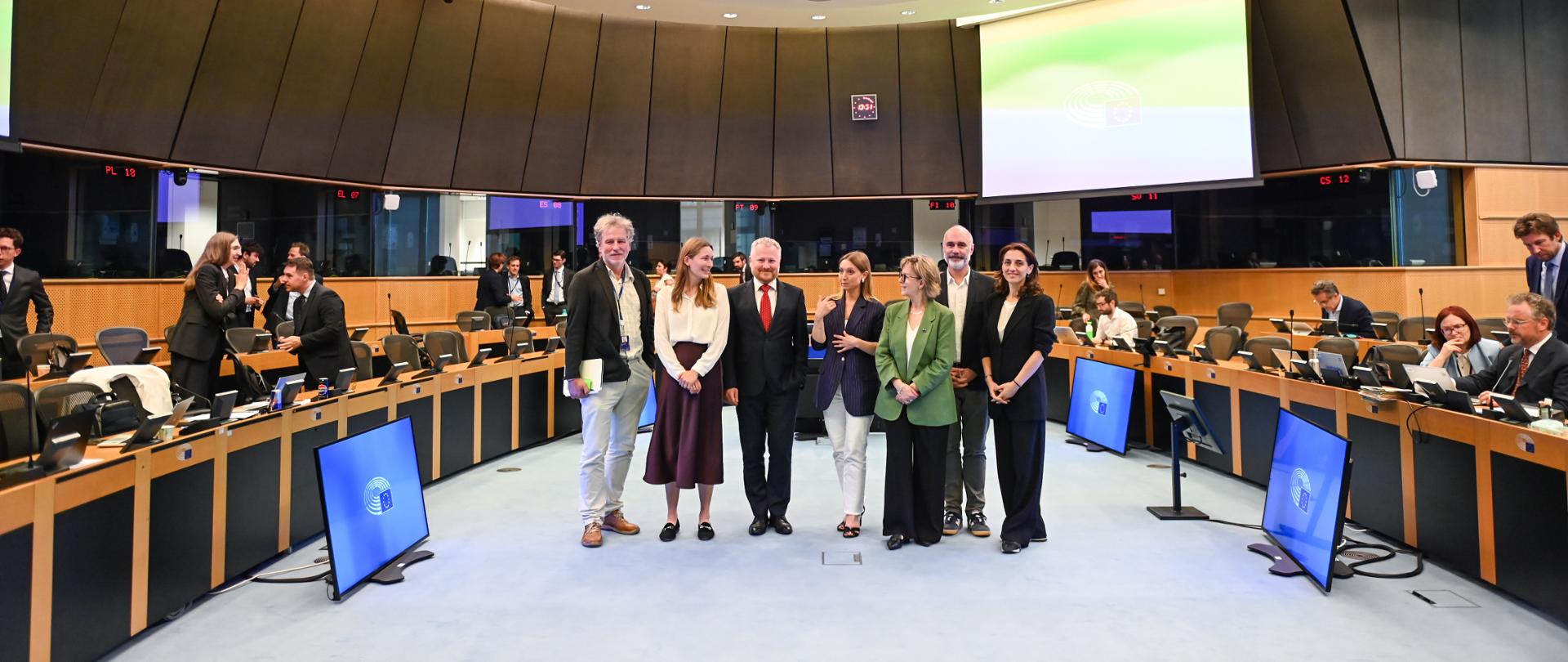 Uczestnicy spotkania stoją na sali obrad