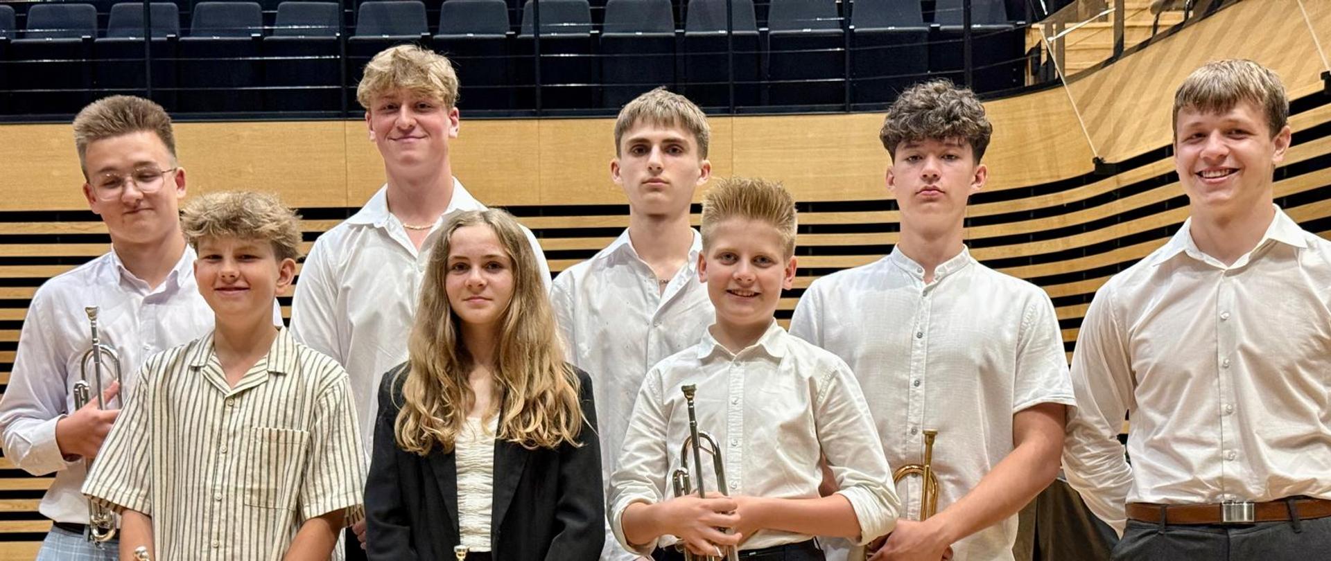 Dziewczyna i siedmiu chłopaków stoi na scenie.