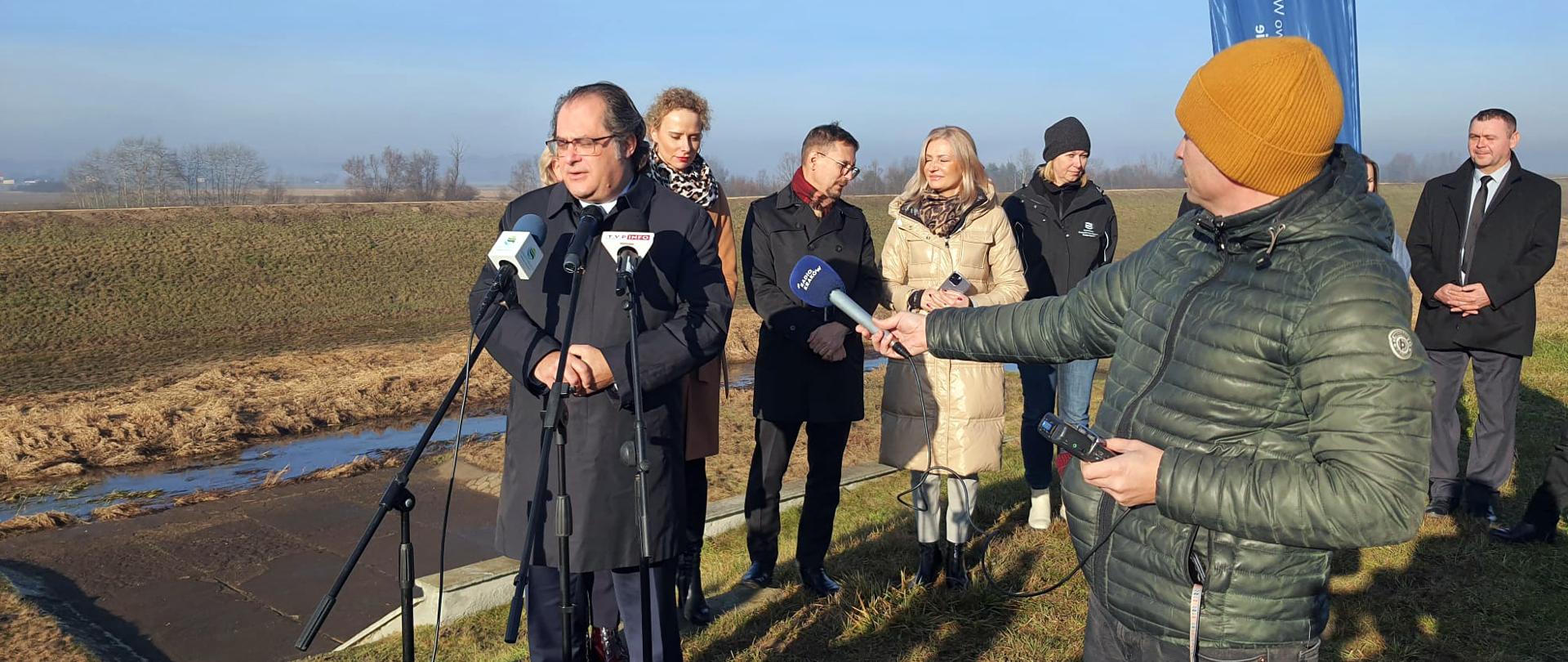Wiceminister infrastruktury Marek Gróbarczyk w trakcie konferencji prasowej na wale przeciwpowodziowym potoku Uszewka