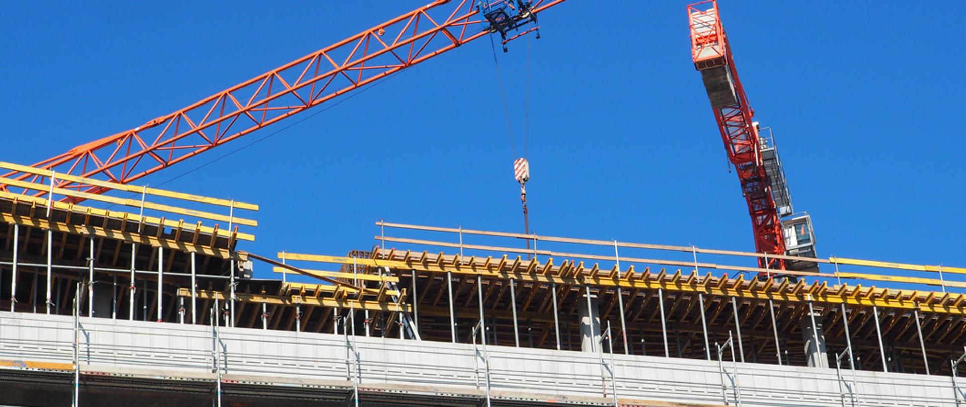 Budowa z dwoma żurawiami i wielopiętrowym budynkiem w trakcie realizacji.