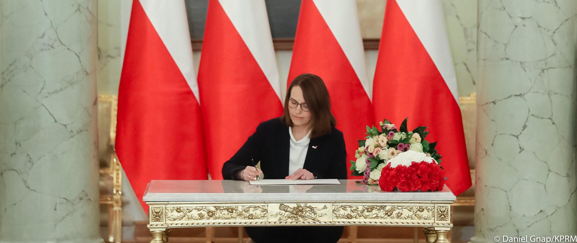 Minister finansów Magdalena Rzeczkowska przy stole, podpisuje akt mianowania