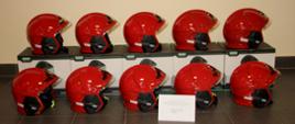 Czerwone hełmy strażackie widoczne z boku stoi na kartonach i na podłodze.