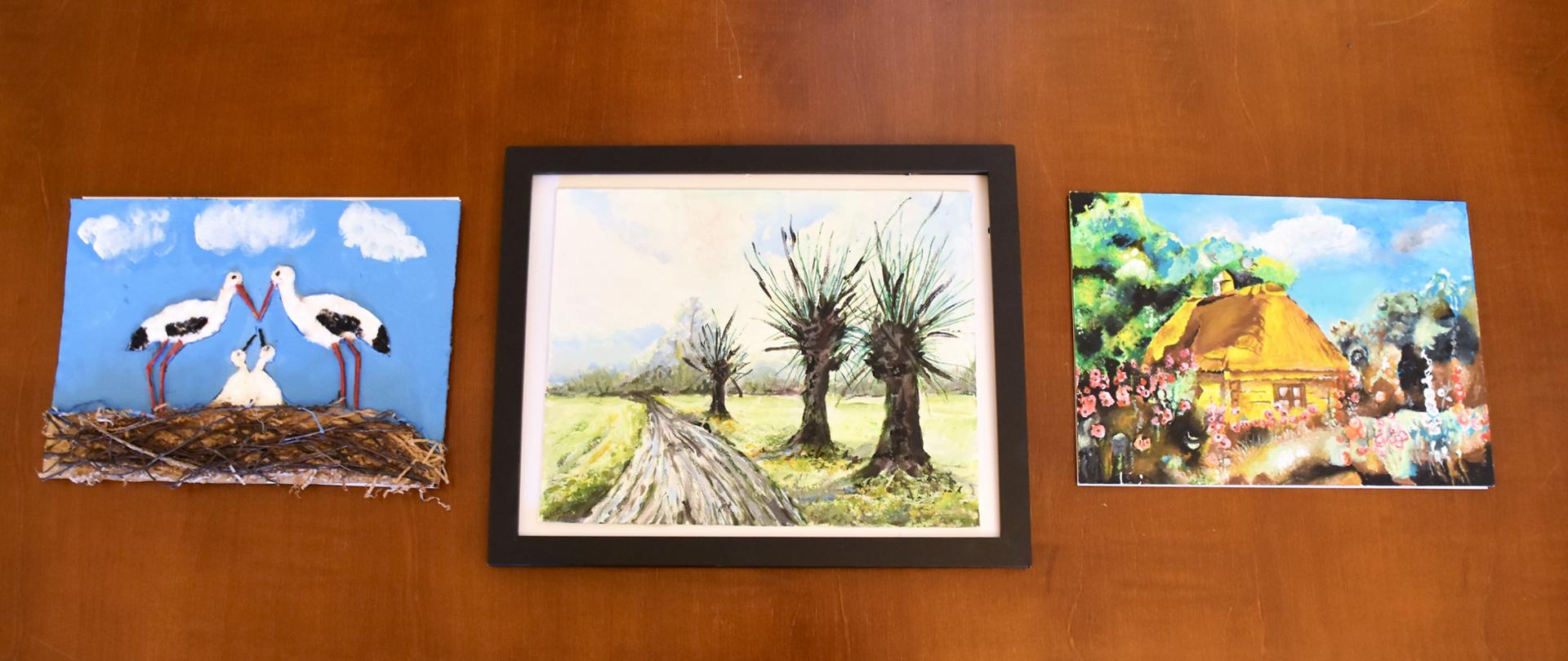 trzy obrazki, pierwszy przedstawia bociany w gnieździe, drugi przedstawia drogę przy której rosną wierzby iwy, trzecie przedstawia drewniany wiejski dom otoczony różowymi malwami