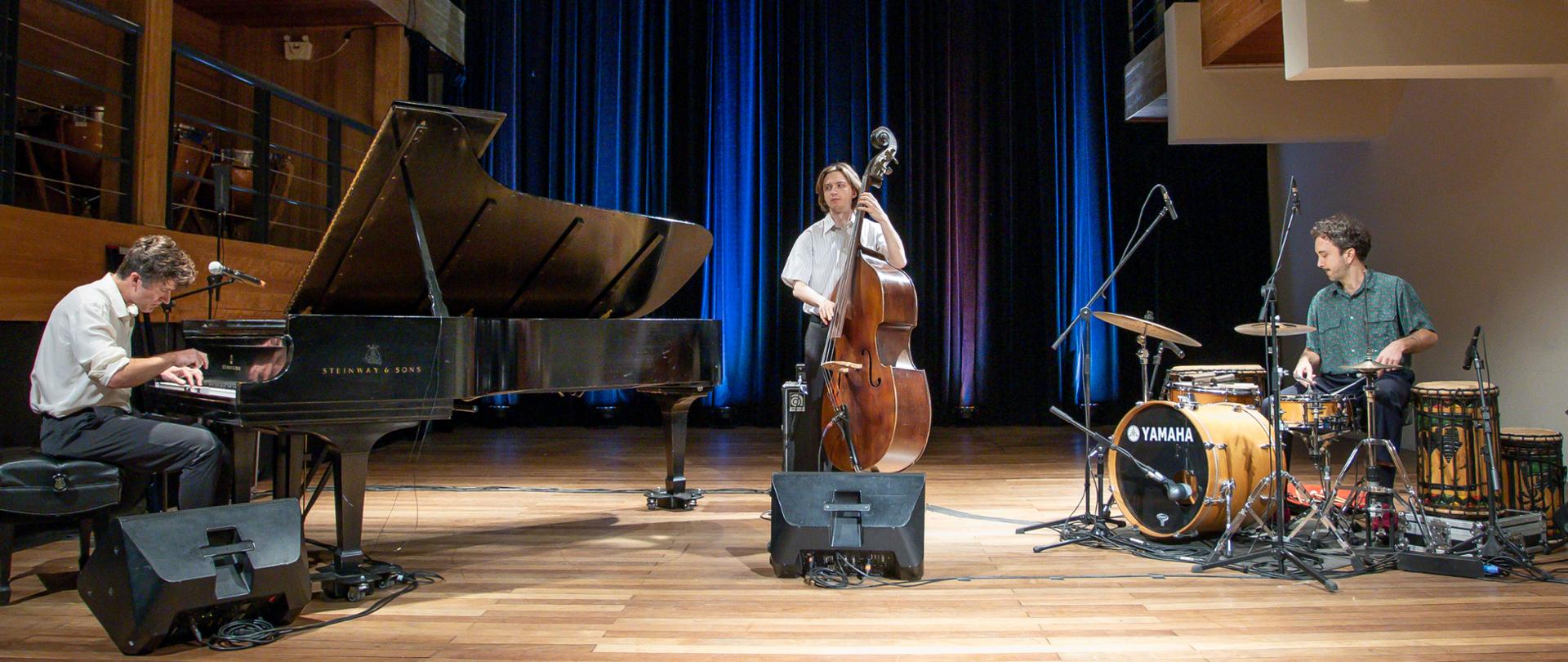 Pianista przy fortepianie Steinway, kontrabasista i perkusista na scenie w Capela Santa Maria w Kurytybie, podczas koncertu