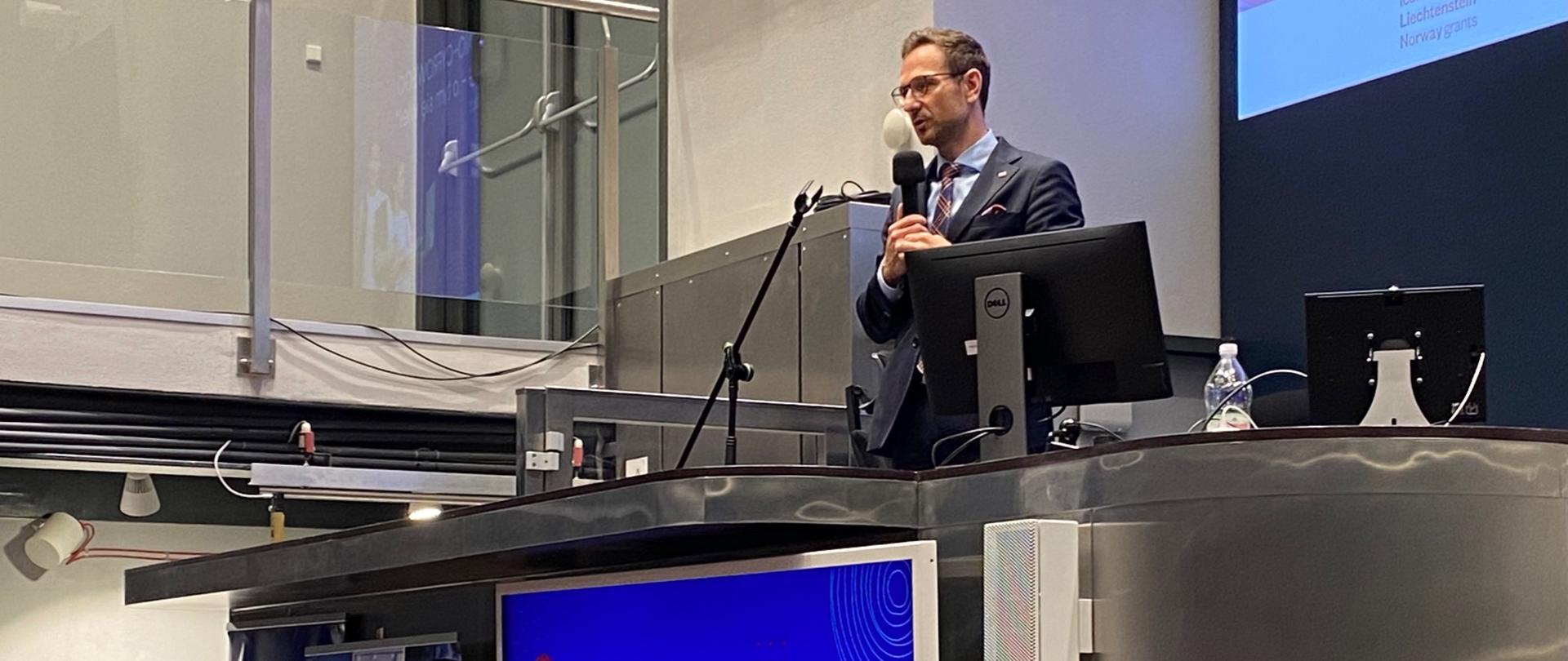 Minister Buda stoi z mikrofonem 