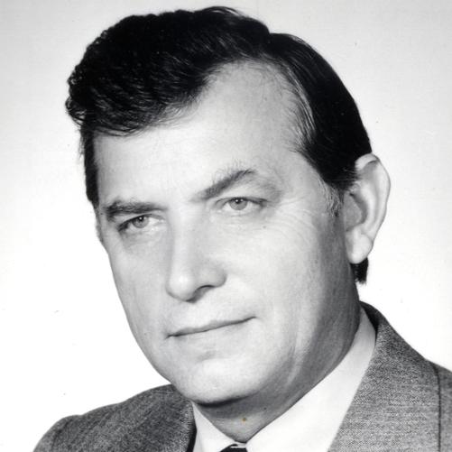 Marian Orzechowski - czarno - biały portret mężczyzny, ciemne włosy, szara marynarka, biała koszula.