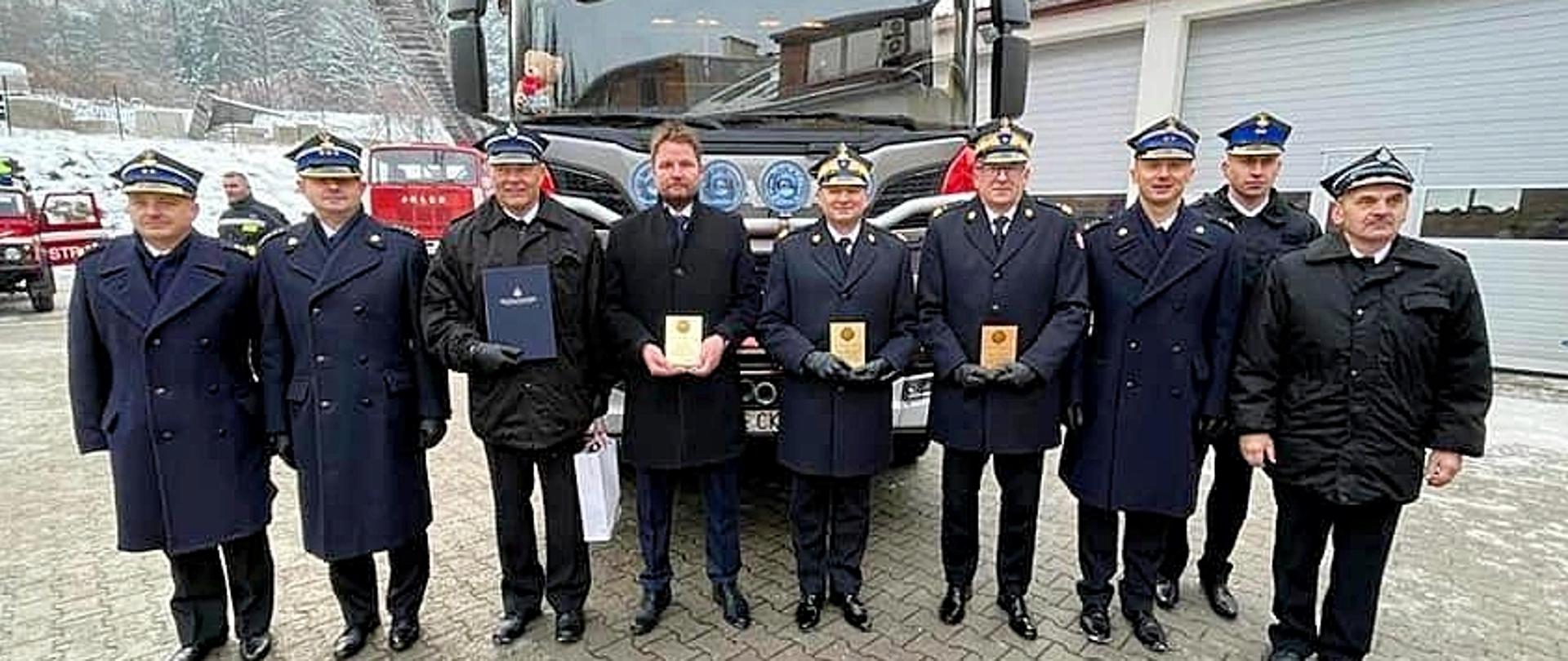 Zdjęcie grupowe na który widoczni są: Burmistrz Karpacza Radosław Jęcek, nadbryg. Adam Konieczny- Zastępca Komendanta Głównego Państwowej Straży Pożarnej, nadbryg. Krzysztof Hejduk- Zastępca Komendanta Głównego Państwowej Straży Pożarnej, st. bryg. Marek Kamiński- Dolnośląski Komendant Wojewódzki Państwowej Straży Pożarnej, bryg. Andrzej Ciosk- p.o. Komendanta Miejskiego Państwowej Straży Pożarnej w Jeleniej Górze. W tle samochód pożarniczy. 