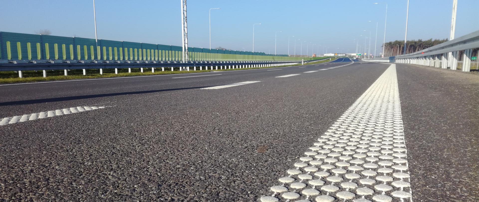 Zdjęcie przedstawia poglądowo drogę ekspresową w oddali. Widok z poziomu drogi.