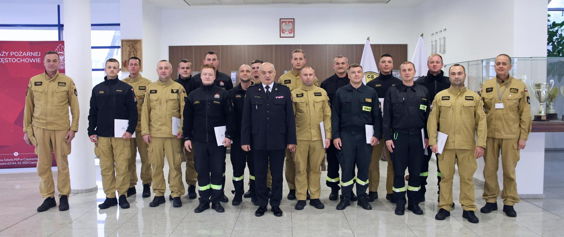 Pamiątkowe zdjęcie grupowe funkcjonariuszy PSP uczestniczących w szkoleniu dla kierowców pojazdów uprzywilejowanych (16 osób) w towarzystwie Komendanta Centralnej Szkoły PSP oraz dwóch oficerów CS PSP