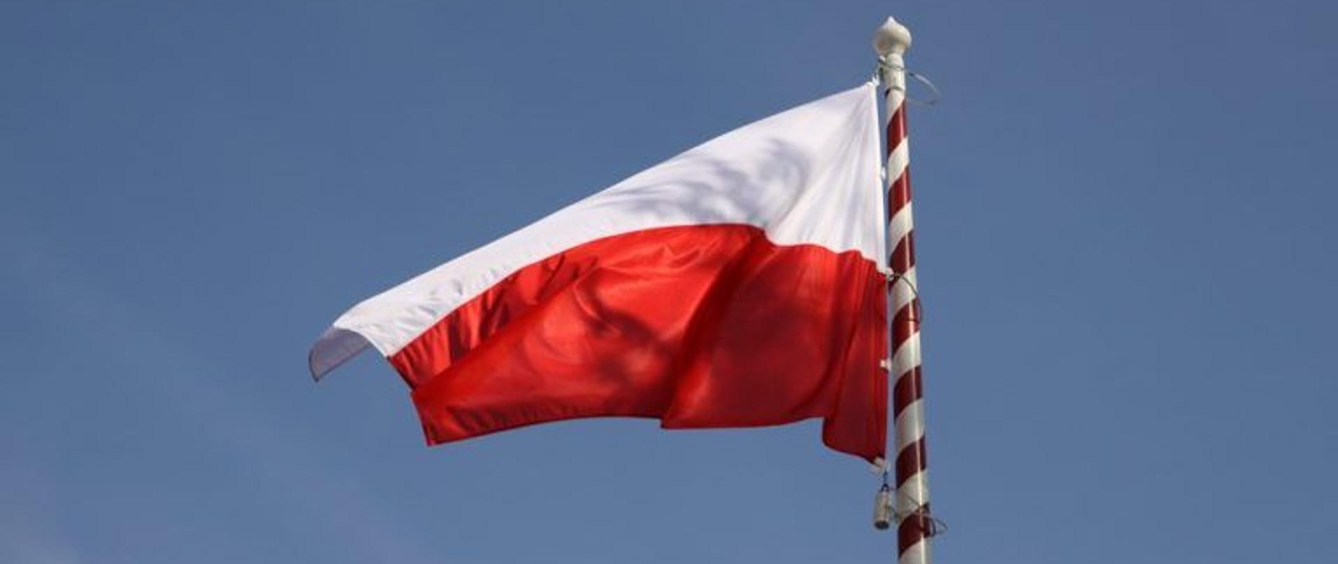 Flaga biało - czerwona powiewająca na wietrze.