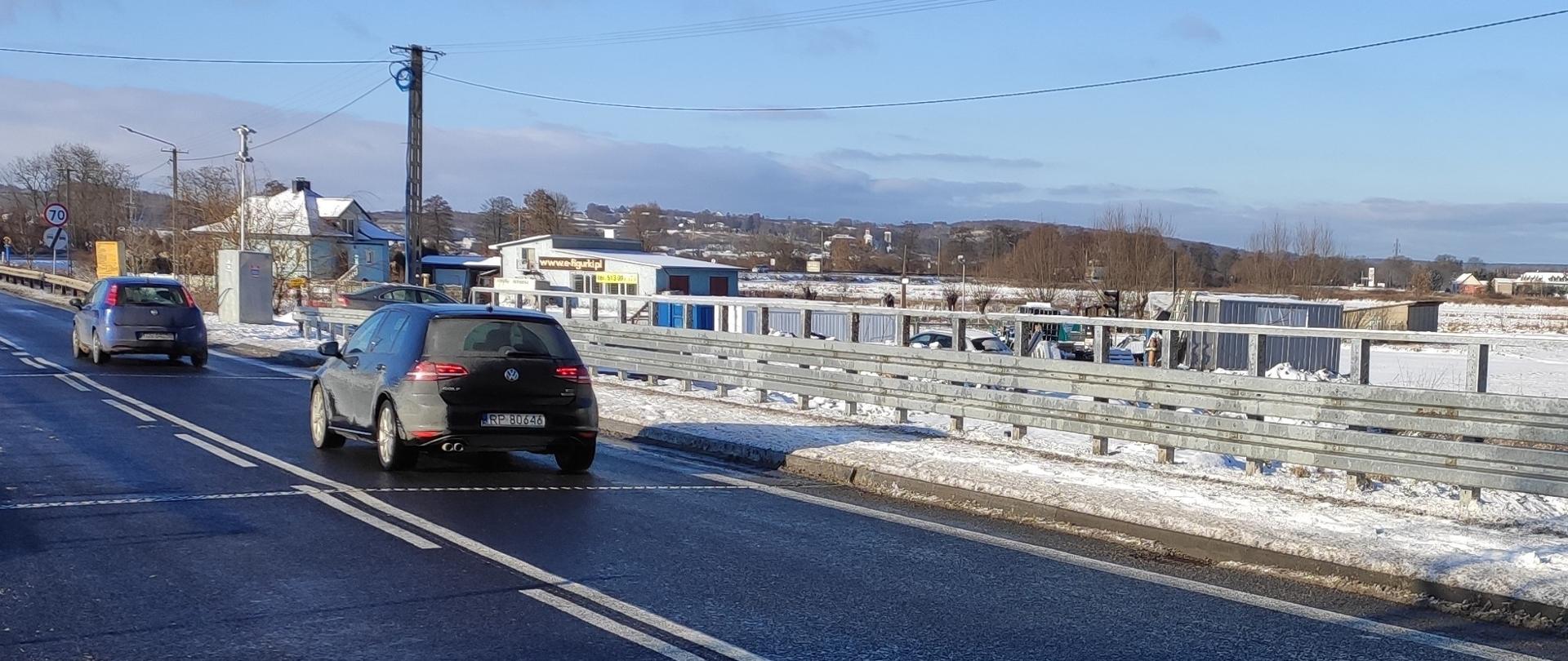 DK9 Rudka - nowy most, jezdnia, chodnik, bariery, jadące samochody, w oddali zabudowania, śnieg