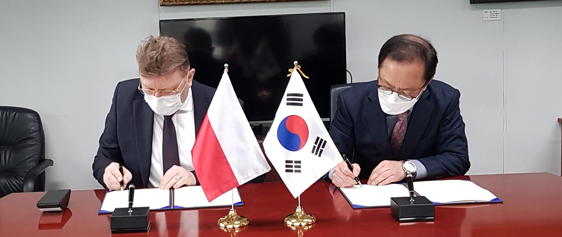 Zdjęcie przedstawia Ambasadora Piotra Ostaszewskiego oraz przedstawiciela MSZ RK podczas podpisywania Planu Działań