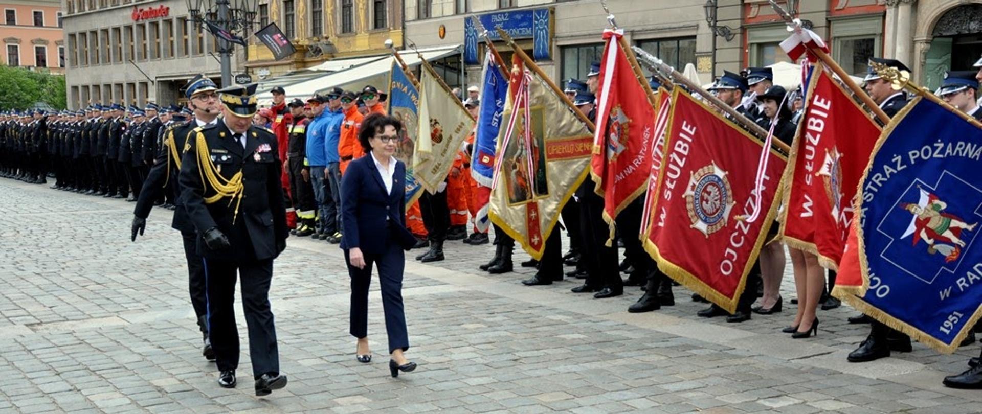 Strażacy z pochylonymi sztandarami podczas przeglądu pododdziałów
