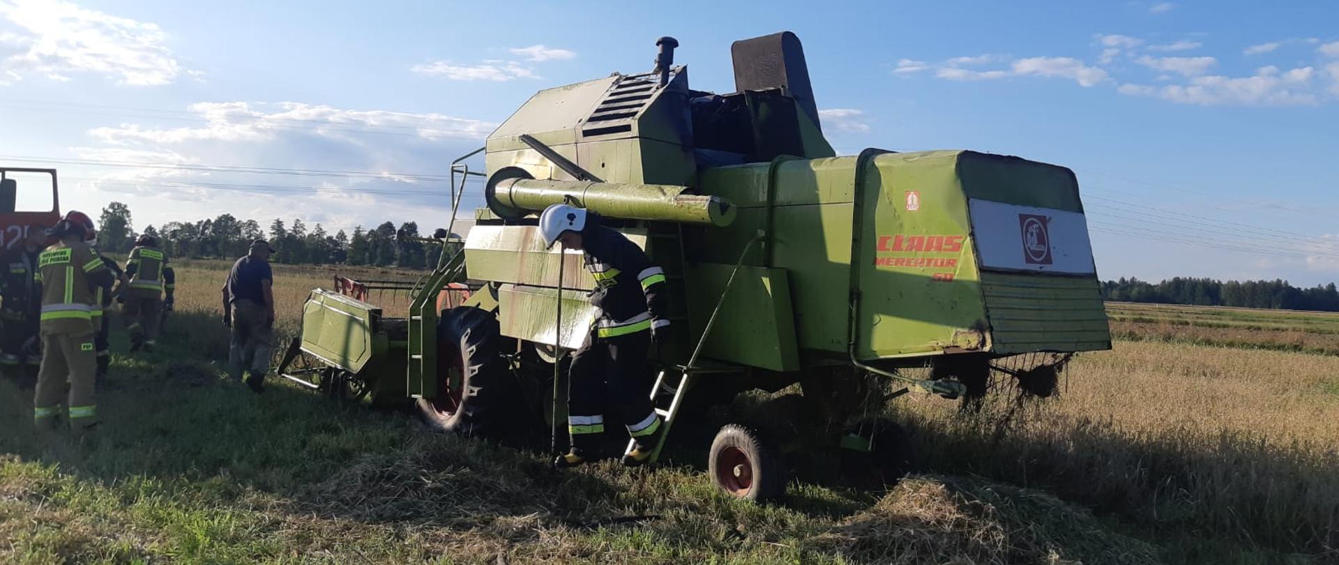 Na zdjęciu widać kombajn zbożowy i strażaków.