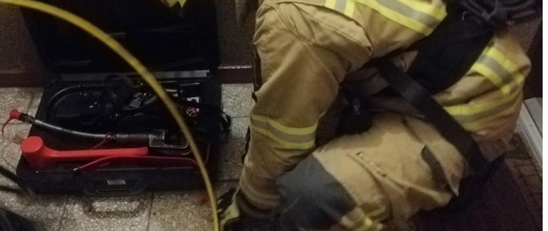 Strażacy sprawiają zestaw hydrauliczny w celu otwarcia drzwi