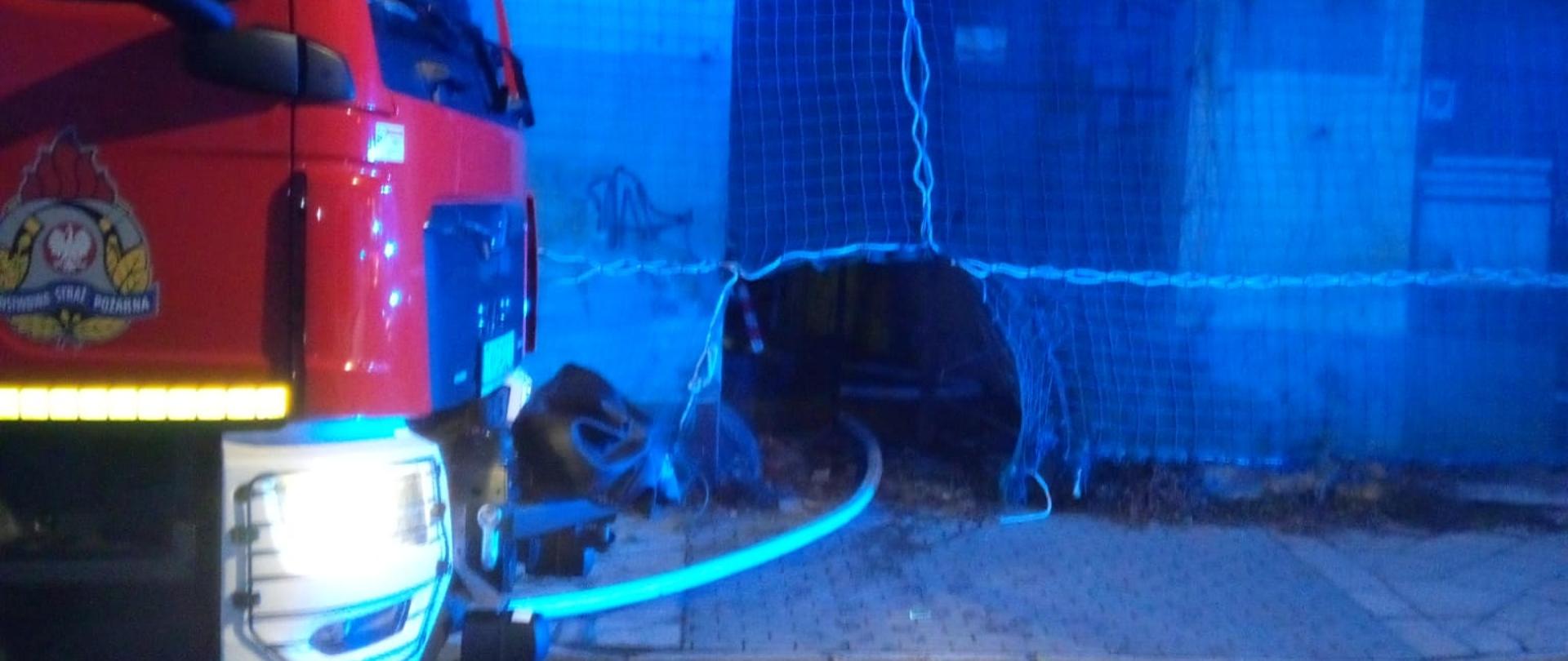 Na zdjęciu pokazano samochód gaśniczy stojący na ulicy Piotrkowskiej a w centralnym punkcie węża gaśniczego wprowadzonego do budynku przez bramę.