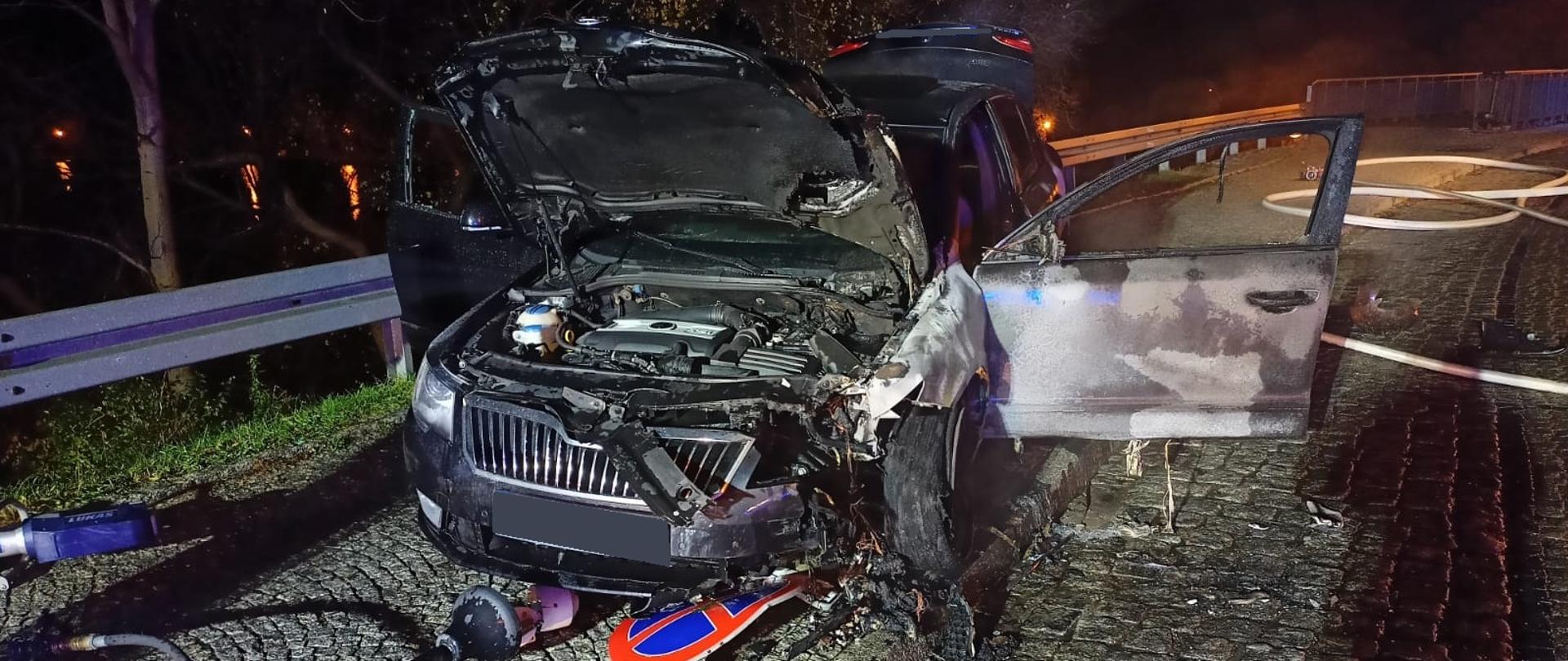 na zdjęciu widać częściowo spalony samochód osobowy, uszkodzoną latarnię