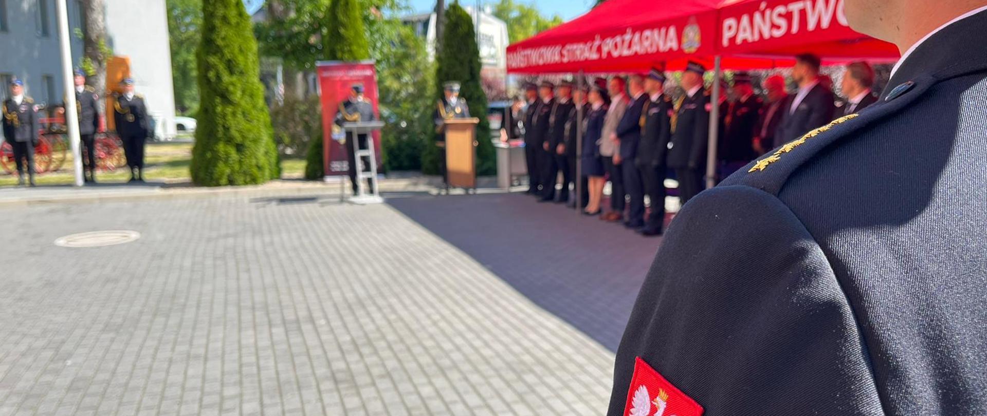 Na pierwszym planie mundur PSP. W tle spiker uroczystości.