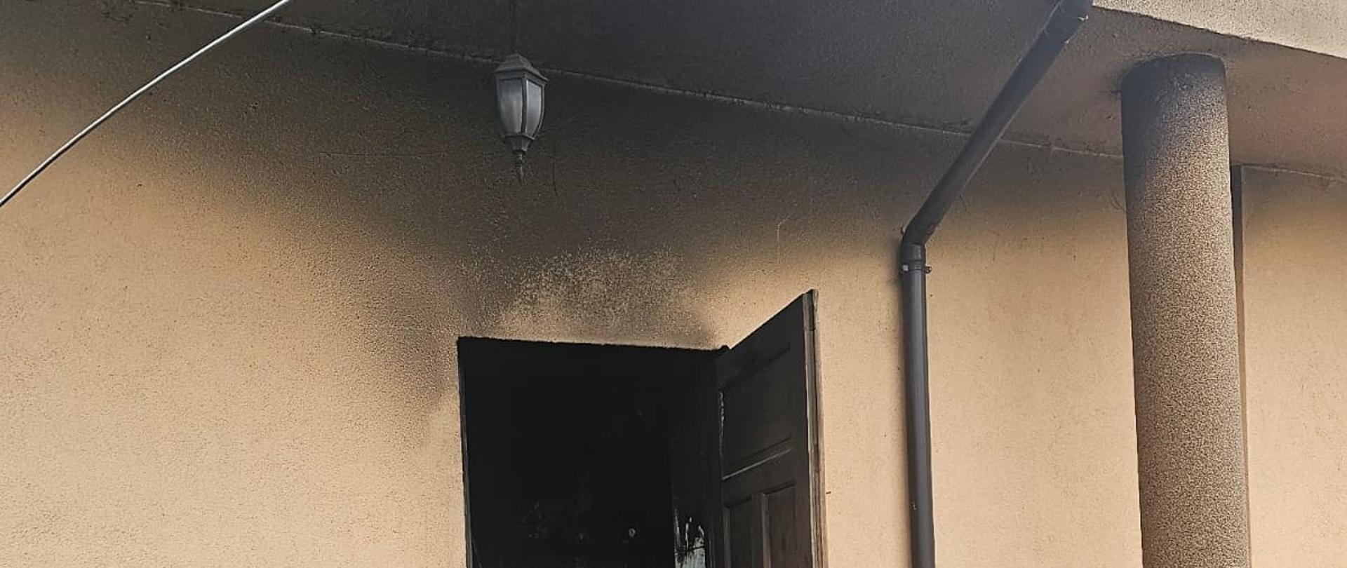 Zdjęcie przedstawia wejście techniczne do budynku od strony kotłowni gdzie wybuchł pożar. Widać okopcenia elewacji.