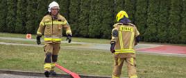 Na zdjęciu strażacy wykonujący zadanie praktyczne na egzaminie - rozwinięcie linii gaśniczej
