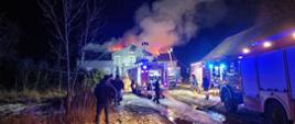 Wiidoczny na zdjęciu pożar dachu budynku mieszkalnego oraz samochody ratowniczo-gaśnicze PSP, OSP i WSP