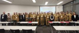 Zebrani strażacy, podczas seminarium w Akademii Pożarniczej w Warszawie, w sali konferencyjnej, na wspólnym zdjęciu.