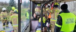 Zdjęcie zrobione w autobusie. Osoby lżej ranne umieszczone w dodatkowym autobusie w celu zachowania komfortu termicznego. Strażacy monitorują stan osób poszkodowanych.