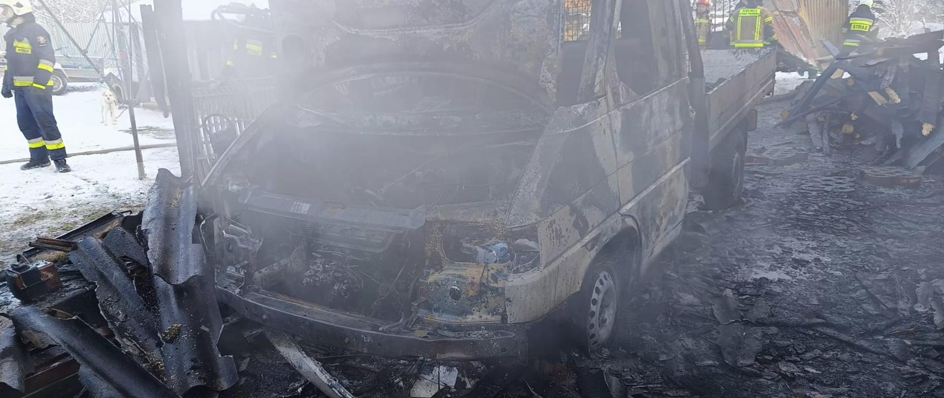 Spalony samochód dostawczy oraz strażacy