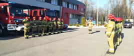 Zdjęcie przedstawia strażaków stojących w szeregu i oddających honor poległym ratownikom na Ukrainie.