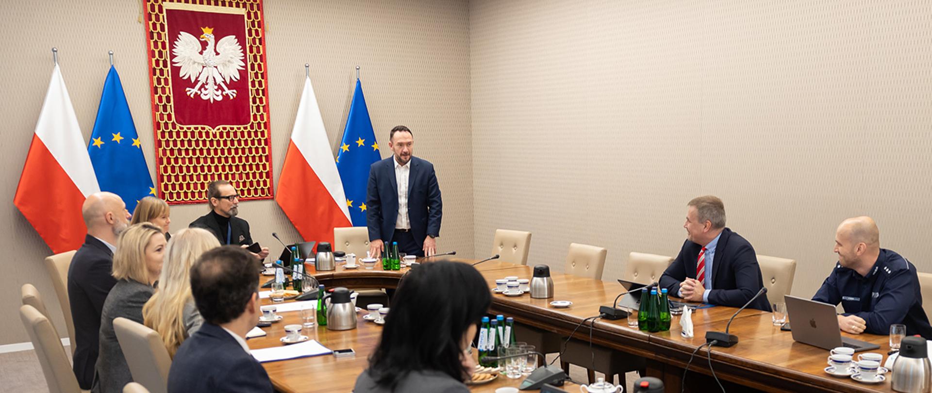 Na zdjęciu widać sekretarza stanu Tomasza Szymańskiego witającego się z uczestnikami spotkania.