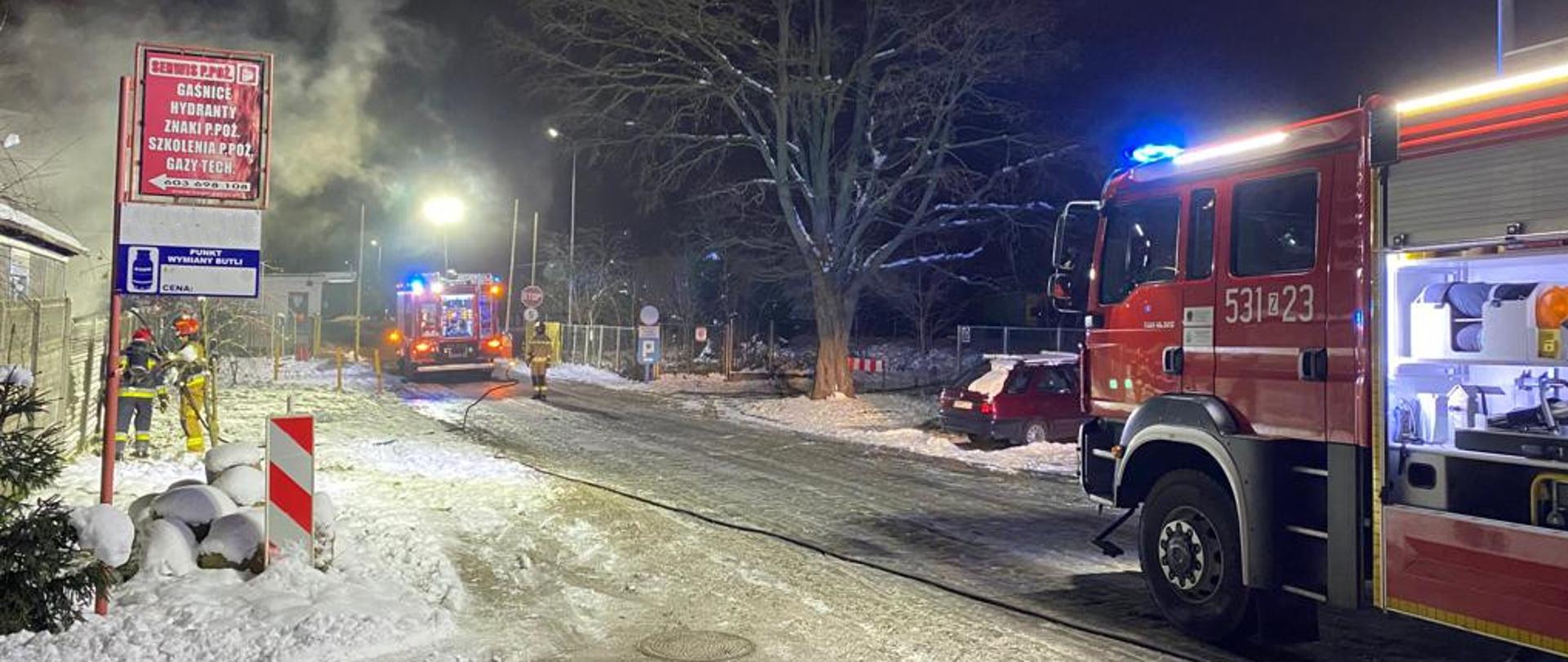 na drodze w odległości od siebie stoją dwa samochody pożarnicze 